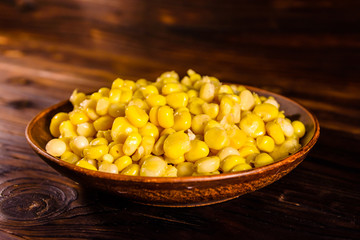Ceramic plate with canned corn seeds on wooden table
