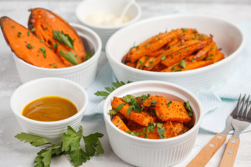 Different types of baked sweet potato with curry and a creamy garlic sauce. White dishes, light background. Healthy vegan food concept.