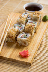Sushi roll with salmon, cucumber and tuna skin on a wooden board. Japanese cuisine