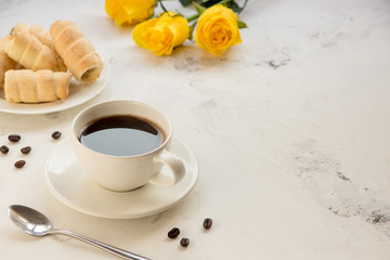Coffee and sweet bakery on a white table, yellow roses on a background