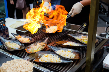 Chopped fresh Atrina pectinata, with cheese on top, are cooked by a flamethrower (Korean street food)