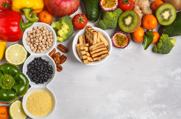 Healthy vegan food concept. Fruits vegetables frame background. Fresh vegetables, exotic and seasonal fruits, tofu, cereals, pasta, nuts and beans for a vegetarian diet, top view. 