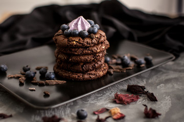  Black biscuits with blueberries on a black matte plate