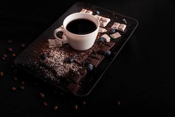 A cup of coffee on a plate with chocolate