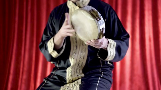 Arabic percussionist playing a decorated riq.