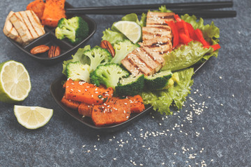 Vegetarian asian salad with sweet potato, grilled tofu, broccoli and pecan. Healthy vegan food concept. Dark background, copy space.