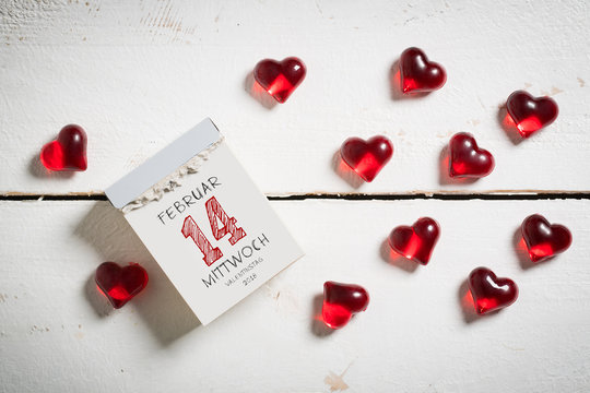 Abreißkalender mit Valentinstag und dekorativen Herzen auf Holzuntergrund