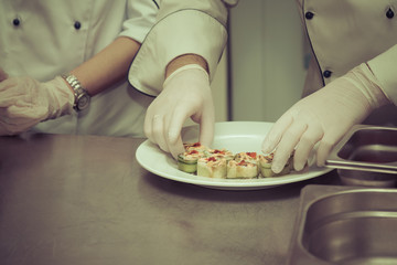 Chef is cooking set of sushi on a metal table of restaurant kitchen. Selective focus. Shallow depth of field. Toned