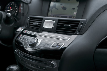 Fototapeta premium Luxury car inside. Interior of prestige modern car. Automatic transmission gear shift. Black perforated leather cockpit. Media control buttons in black leather with navigation computer monitor screen