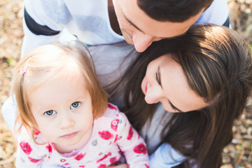 Young loving family of three, authentic candid outdoors family portrait