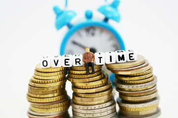 Overtime concept with businessman miniature under the time pressure at work
