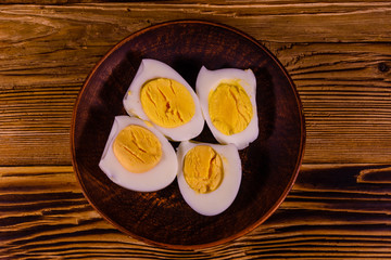 Ceramic plate with peeled boiled eggs on wooden table. Top view