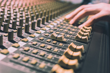 male sound engineer hands working on sound mixer, focus on fader. recording, broadcasting, music...
