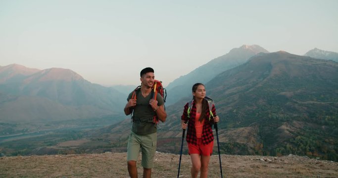 young asian couple of tourists doing selfie reaching the top of the mountain