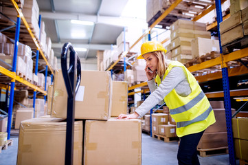Woman warehouse worker with a smartphone.