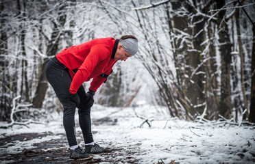 Winter running exercise, runner wearing warm clothes has break