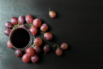 Grape juice separated in glass on a wooden table with grapes.Top view with copy space