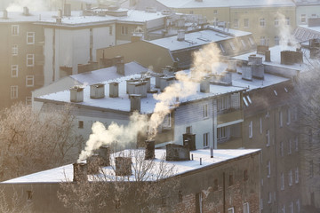 Smoking chimneys in Szczecin city at sunrise indicate burning of wood and coal in old home heating...