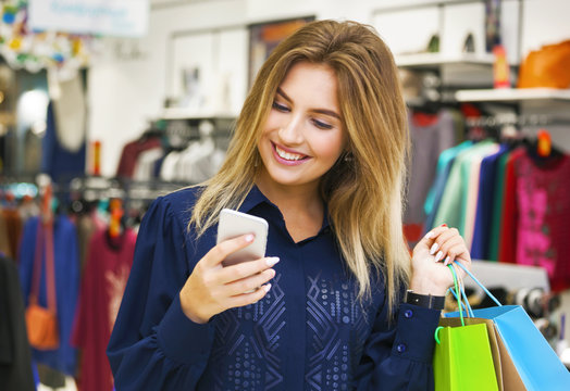 Beautiful woman with shopping bags looking at her phone.