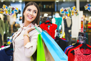 Portrait of beautiful young woman with shopping bags in clothing store.