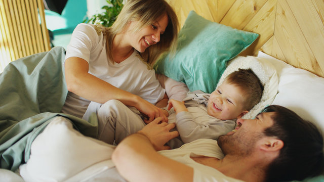 Happy Family Wake Up And Play In Bed At Home