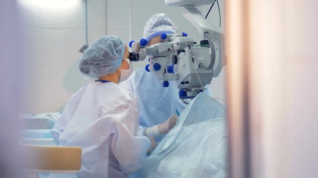 A surgeon and as assistant are engrossed during an eye treatment. 