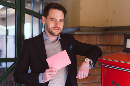 Handsome elegant man post a letter and show pink blank envelope on Valentines Day.