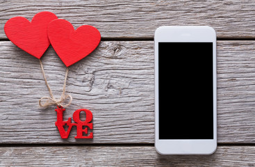 Mobile phone on rustic wood with couple of red hearts
