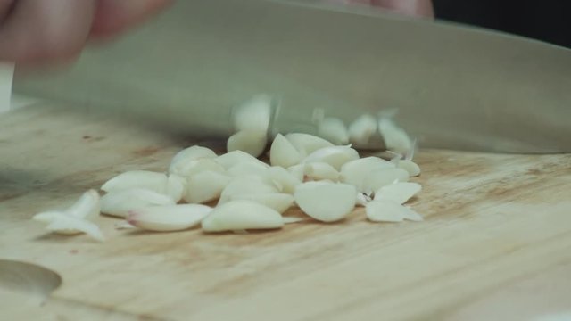 Closeup of chef&rsquo;s hands chopping garlic on cutting board