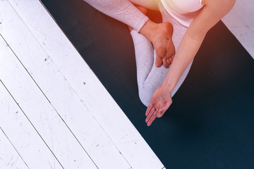 Closeup of young woman in white sportswear sitting in yoga meditation pose.
