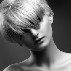 Black and white fashion beauty portrait of a blonde girl with a stylish short haircut, a fringe closes her eyes.