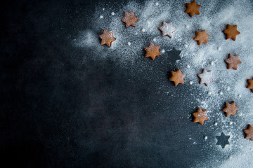 Christmas gingerbread star cookies on the dark blue surface sprinkled with powdered sugar, top...