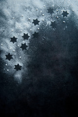 Dark blue background with a star shaped cookies in powdered sugar, top view. 
