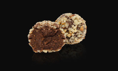 Chocolate truffle on a black background with reflection. One whole and a half Homemade sweets with clipping path