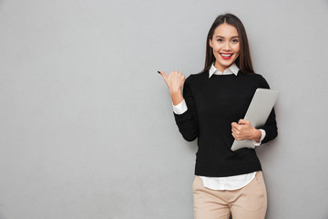 Smiling asian woman in business clothes holding laptop computer
