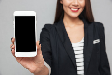 Cropped image of smiling business woman showing blank smartphone screen
