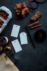 Gift wrapping of Christmas gingerbread cookies. Tags and pencil. Seasonal background shot from above. Materials and accessories for wrapping gifts. Flat lay. Dark background.