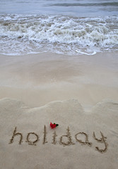 Fototapeta premium The word holiday written on the beach 