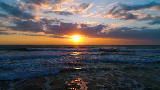 Aerial video of beautiful sunrise with dramatic cloudscape over the sea waves