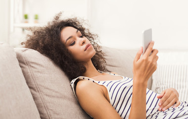 Young girl using mobile phone on sofa