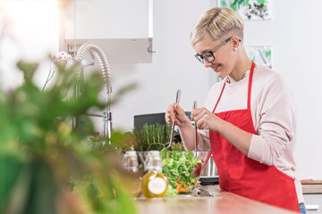 Smiling woman prepairing salad in the kitchen