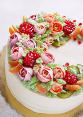 Festive cake with cream flowers and fruits on a light background