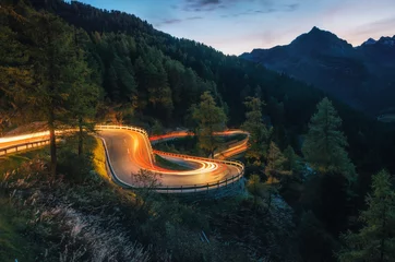 Wandcirkels tuinposter The winding mountain road with light tracks from cars at the evening, Maloja Pass, Switzerland © bortnikau