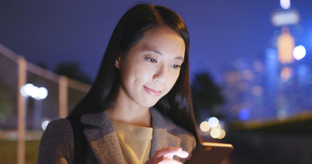 Woman use of mobile phone in city at night