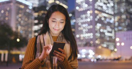 Woman use of smart phone in Hong Kong city at night