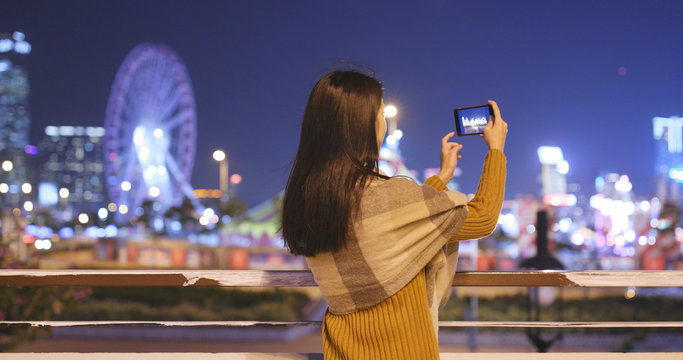 Woman taking photo in the city on cellphone at night