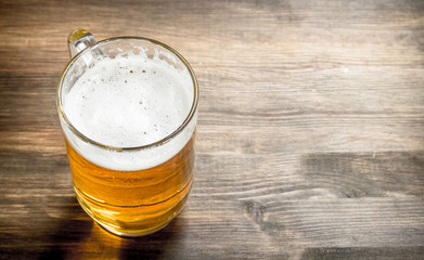 mug of fresh beer. On wooden table.