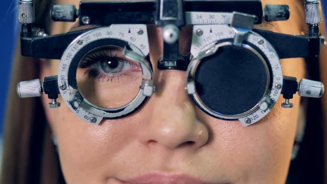 A doctor changes lenses inside a womans trial frame.   