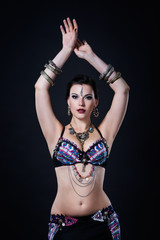 Women performs belly dance in ethnic dress on black background