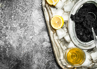Black caviar with white wine and slices of lemon.